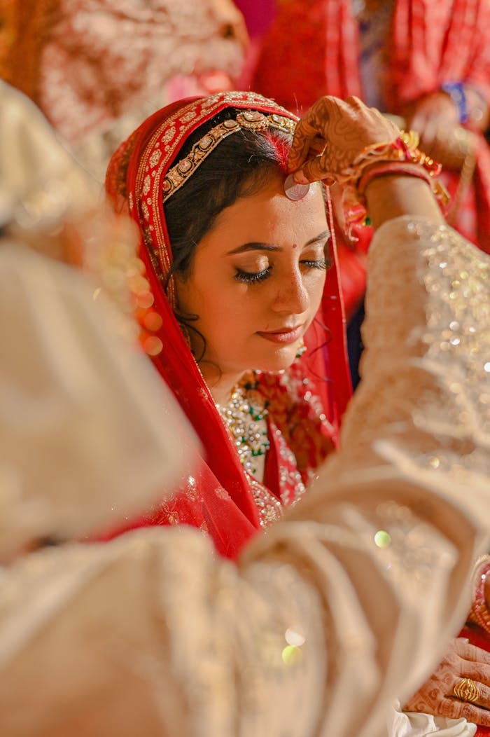 Bride in traditional red saree during an Indian wedding ceremony, showcasing cultural beauty.