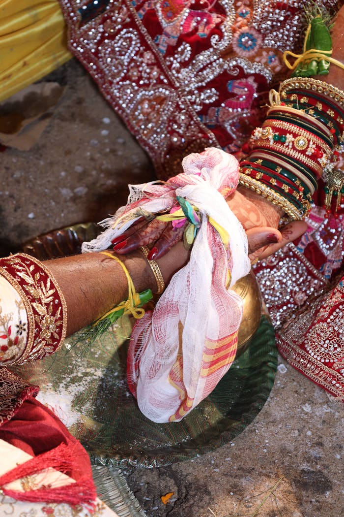Close-up of Indian wedding ritual featuring hands with henna and traditional attire.